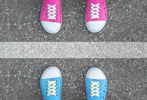 Blue shoes and pink shoes standing on asphalt concrete floor and white line between them